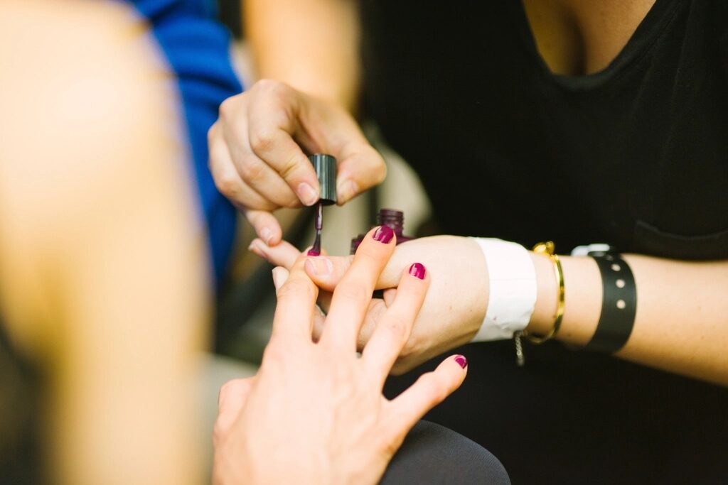 Client's hand being painted a deep plum