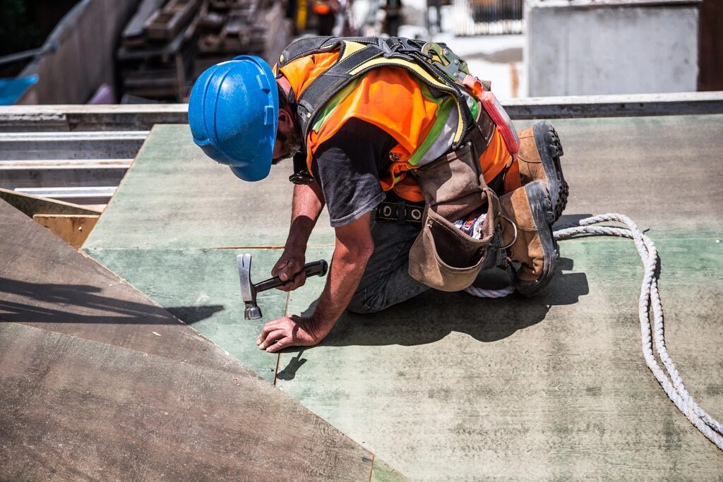 Roofer fastening a sheet while wearing a safety harness